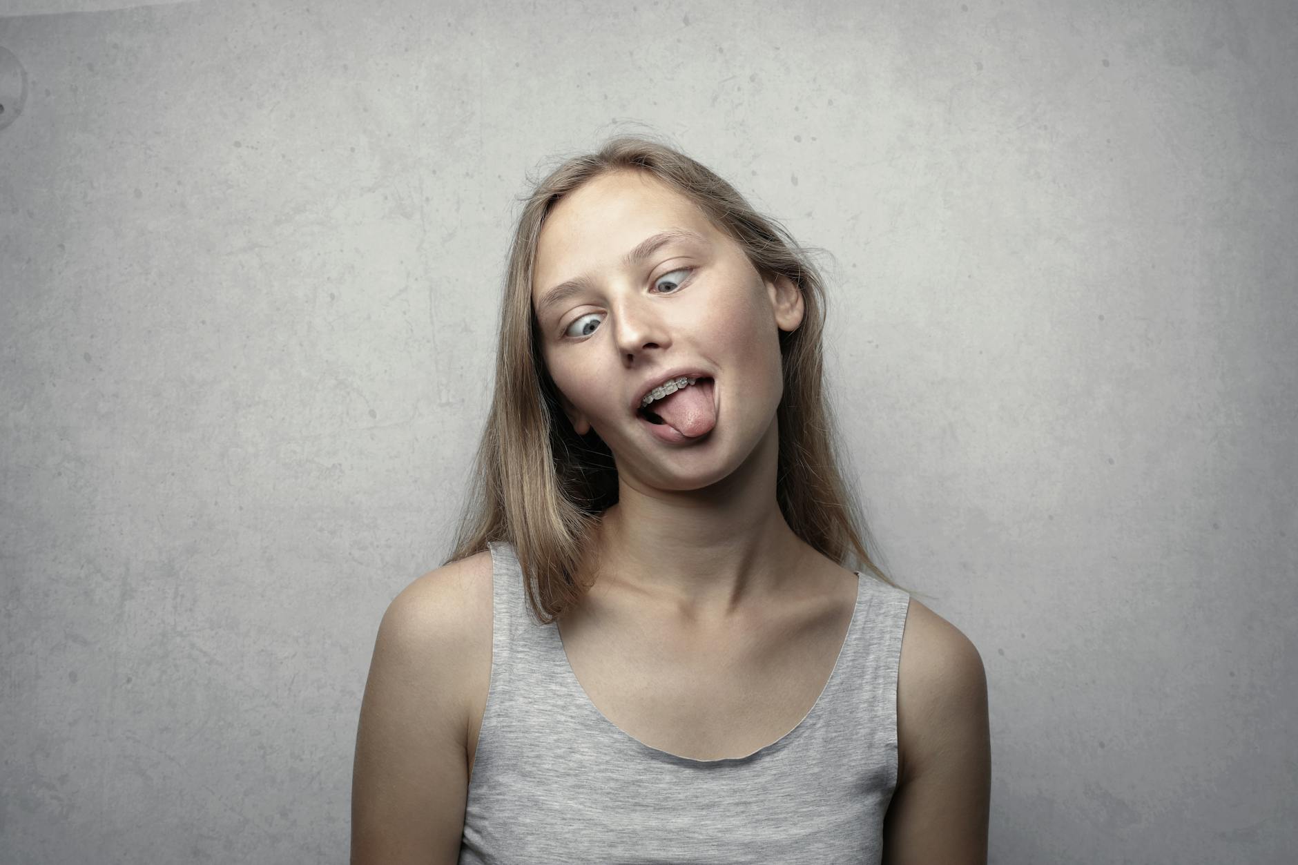 Dilini çıkarırken Gri Kolsuz Bluzlu Kadın