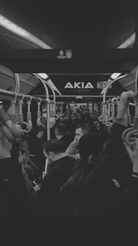Ayakta duran yolcuların bulunduğu kalabalık bir otobüsün içini gösteren siyah beyaz fotoğraf.