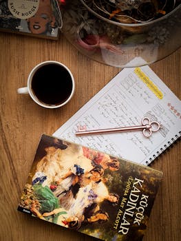 Kitap, defter, kahve ve dekoratif bir anahtarın yer aldığı, samimi bir düz yerleşim fotoğrafı.