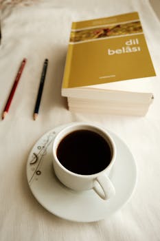 Masada kahve, kitaplar ve kalemlerin bulunduğu, sıcak ve davetkar bir okuma ortamı.
